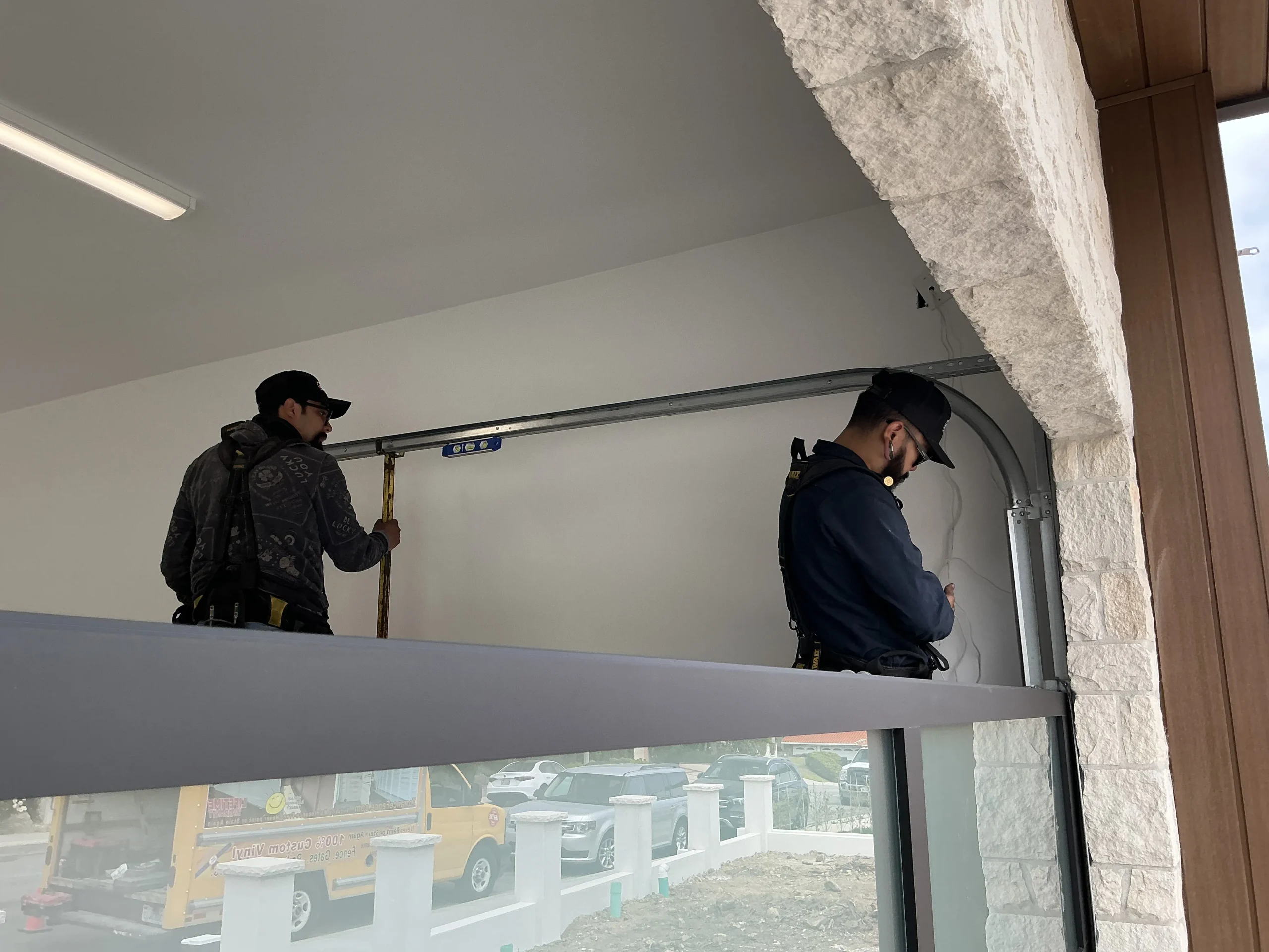 Two technicians adjusting and leveling top track components during an Emergency Garage Door Repair.
