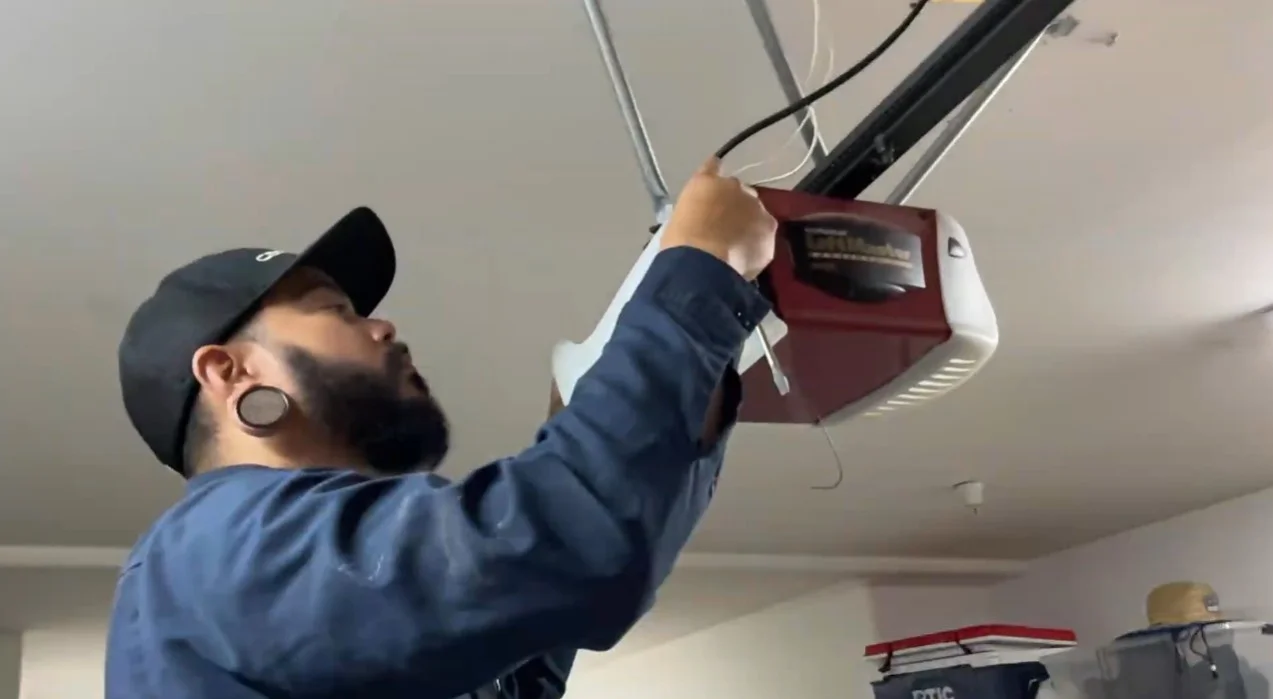 A technician using a tool near the back terminal housing to perform Garage Door Opener Maintenance.