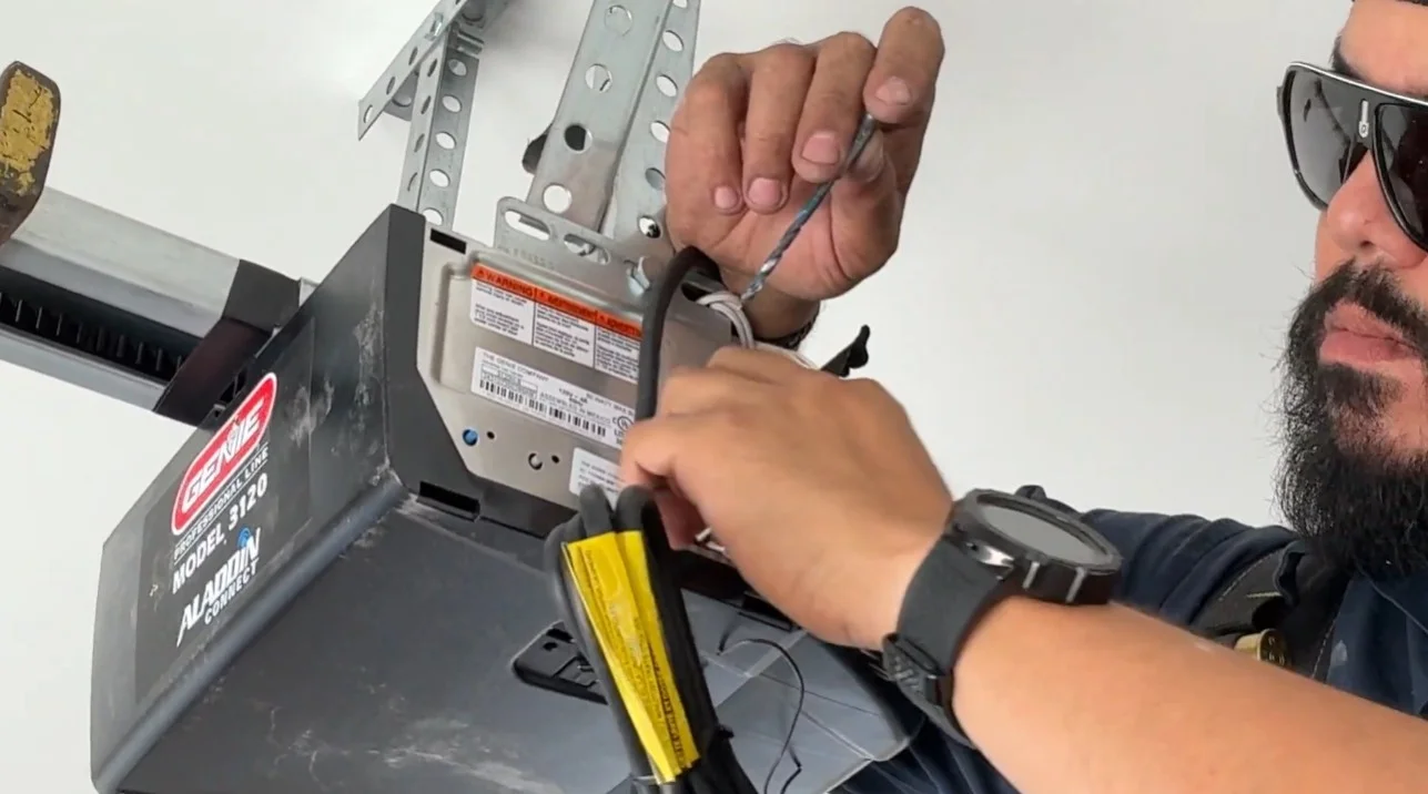 A close-up of a technician connecting wiring to a overhead motor unit during Garage Door Opener Repair.