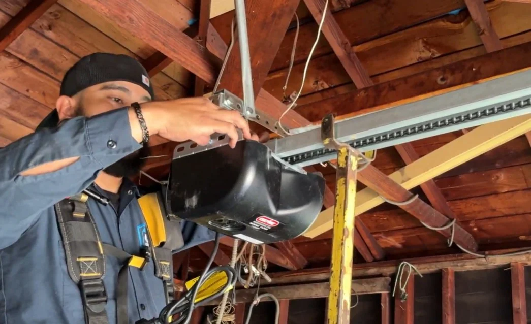 A technician working directly on the overhead motor unit to showcase Professionals Garage Door Opener Repair.