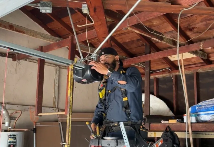 A technician reaching up to adjust memory settings on a ceiling-mounted unit to Reset a Garage Door Opener.